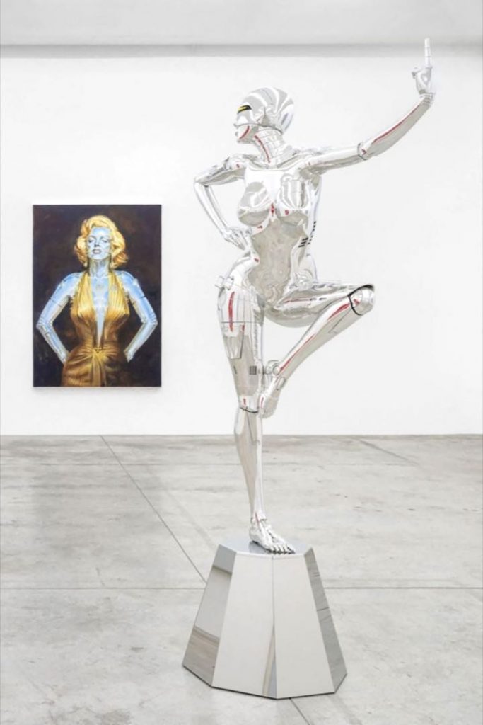 Una mujer robot, protagonista de "Cyber Ladies World" de Hajime Sorayama, y detrás brilla una representación de Marilyn Monroe. 