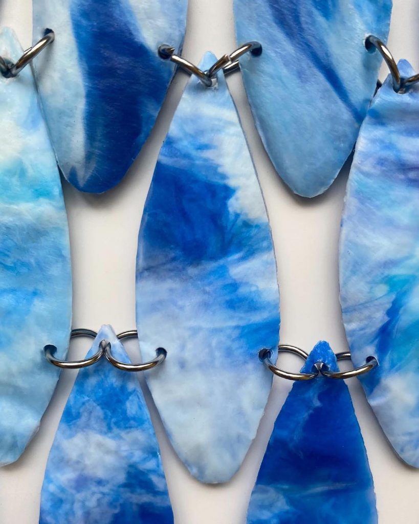 Es un mini vestido en tonalidades azules y celestes degradadas completamente hecho con tapa de botellas de plástico. 