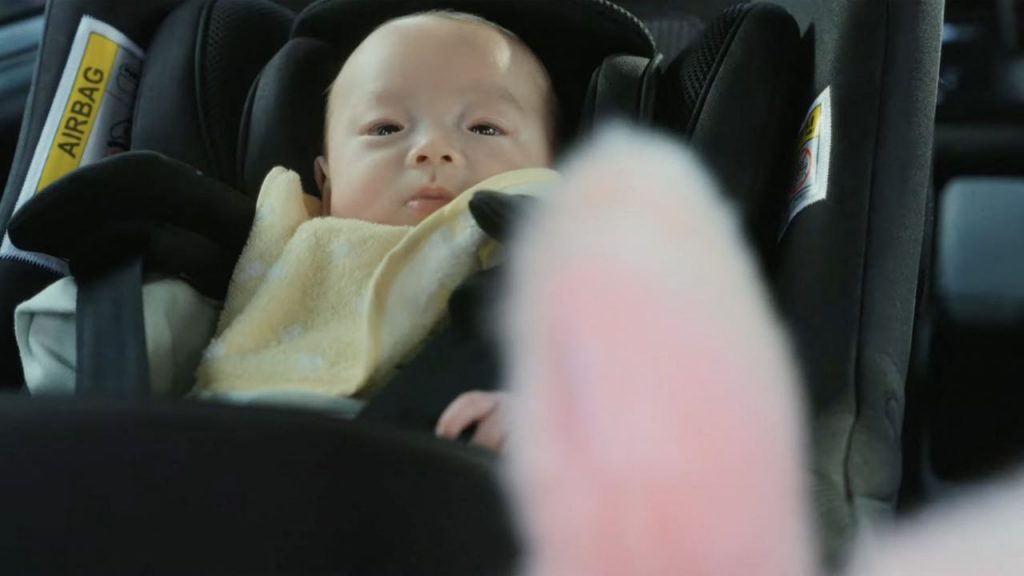 Un bebé mira atentamente al adorable robot de peluche Iruyo durante un viaje en auto. 