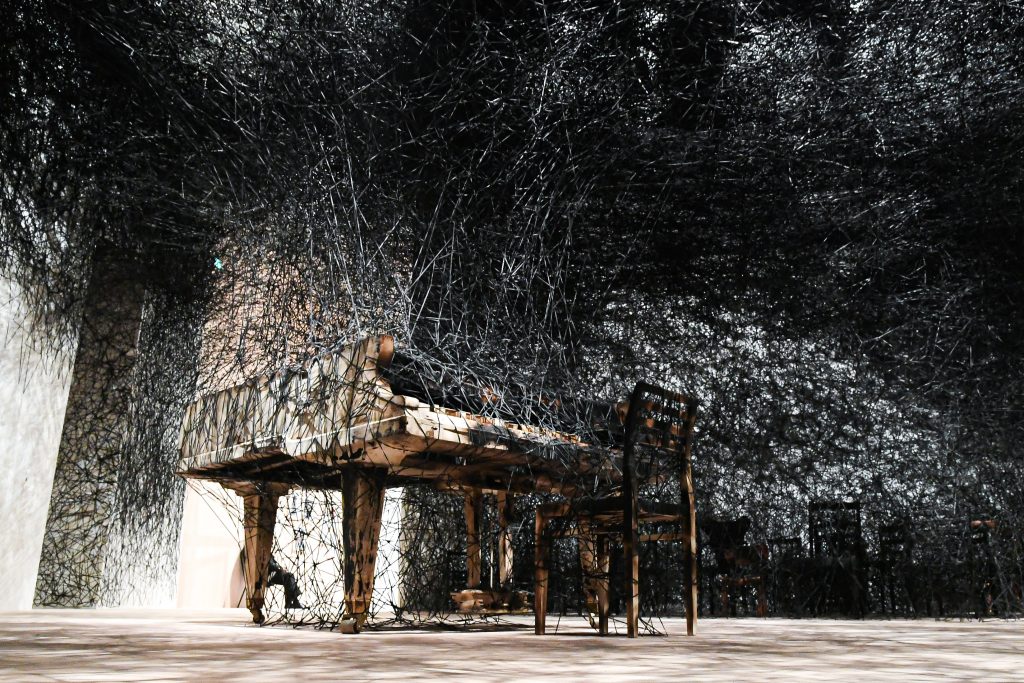 El piano atrapado en una telaraña oscura es una de las instalaciones más contundentes de Chiharu Shiota. 